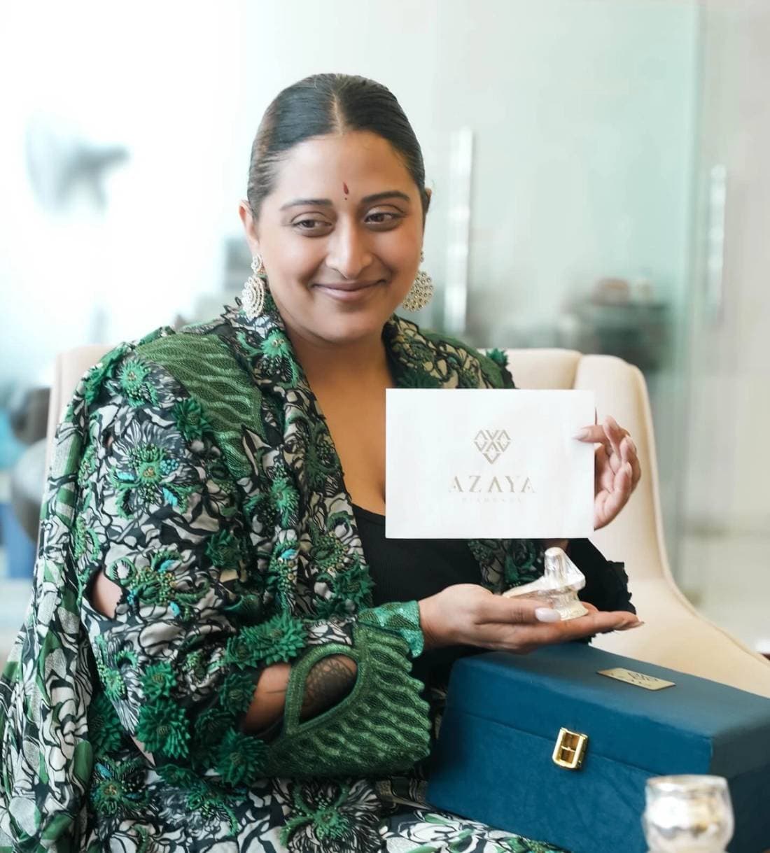 Woman in a green silk outfit holding an Azaya Diamonds gift box